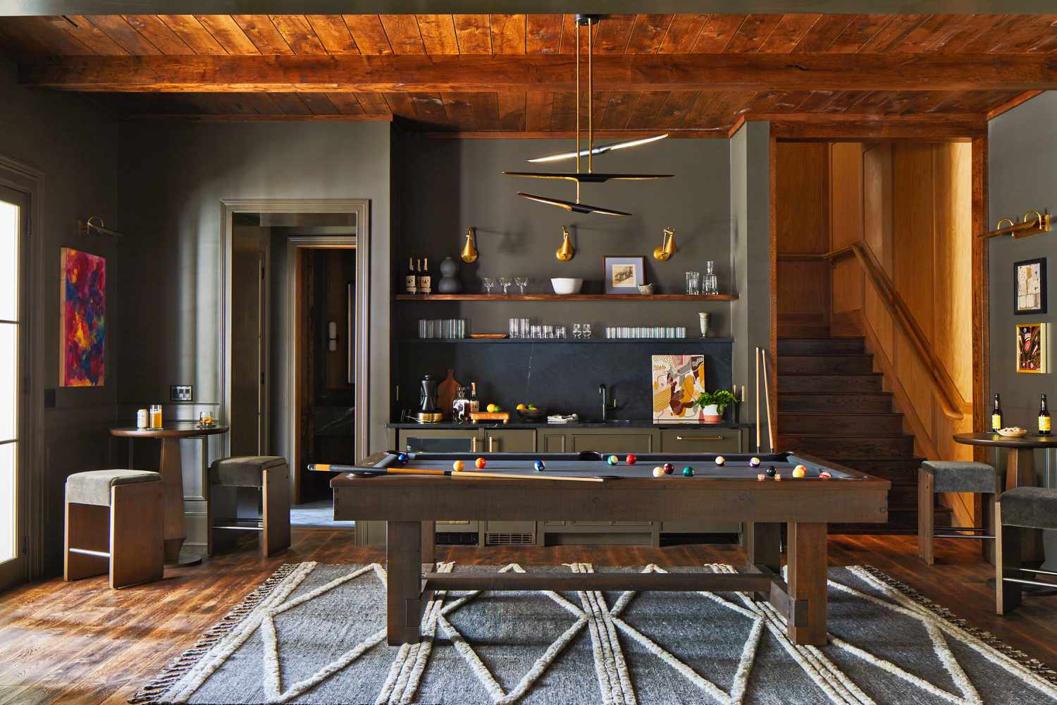 Finished basement game room with wood plank ceiling, pool table and wet bar